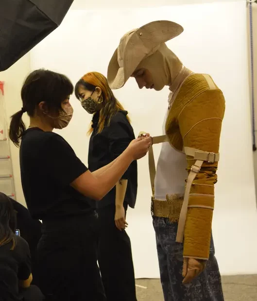 Asian person fitting designer outfit with straps to model