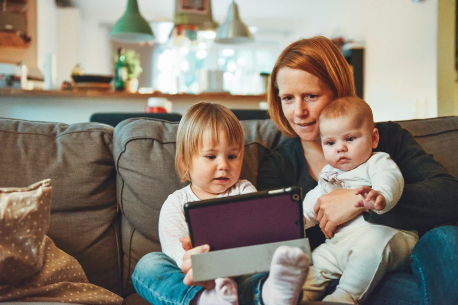 mother and babies sat on sofa looking at tablet device