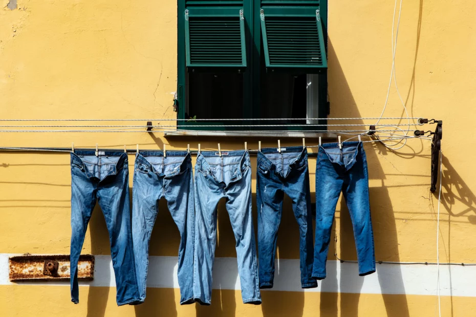 jeans hanging on clothes line under window of yellow painted building