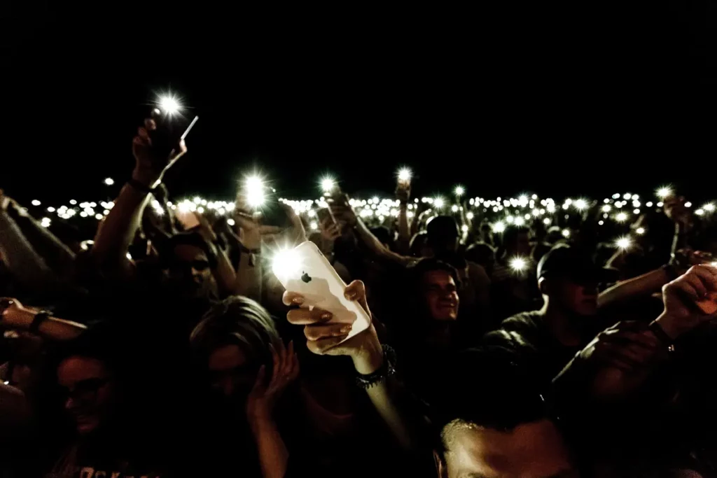 crowd in dark with mobile phone torches lit