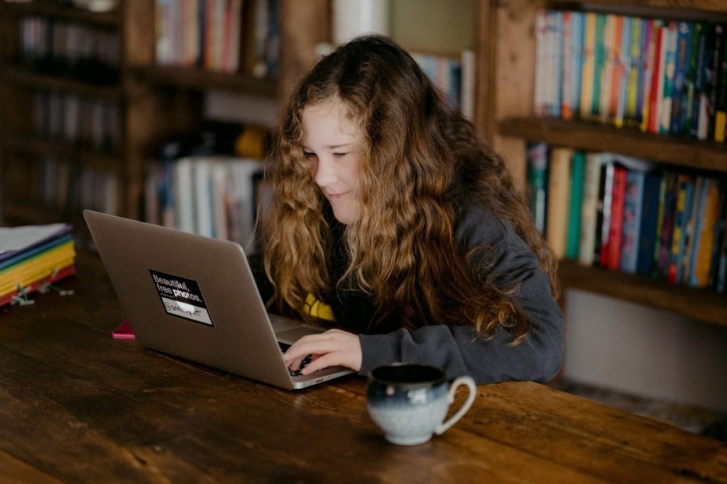 Image of school girl in library looking at laptop - courtesy of Annie Spratt