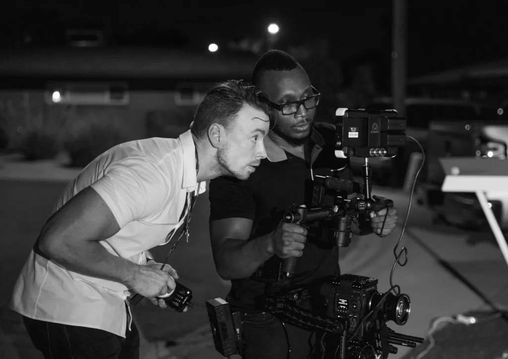 black and white photo of two men with a film camera