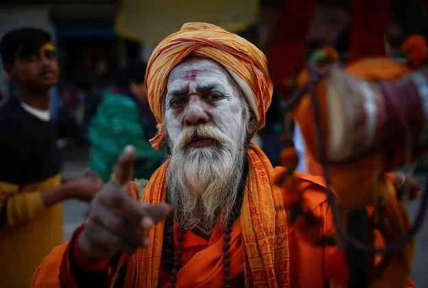 Man wearing orange with painted face at a festival.
