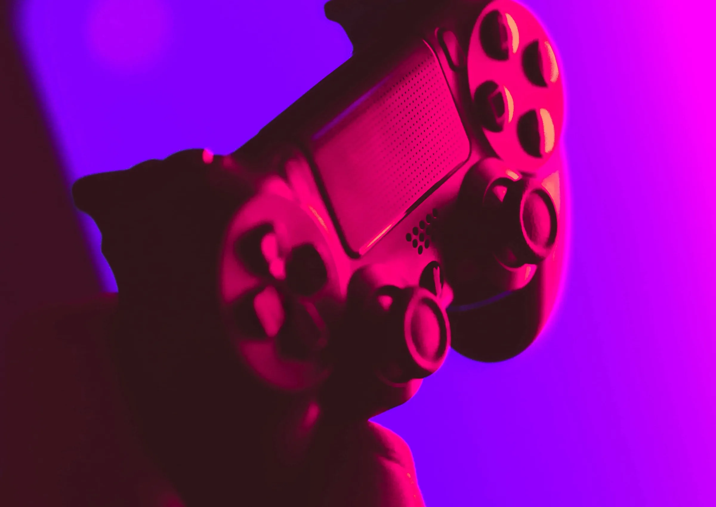 Image of video game controller under pink lighting with a purple background
